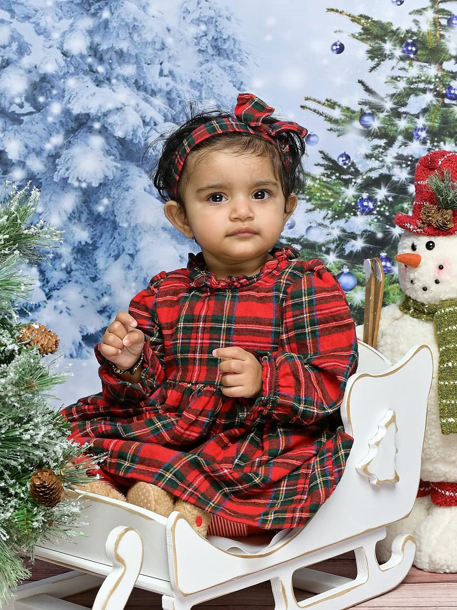 Photo of a baby sitting in a sleigh in a Christmas scene